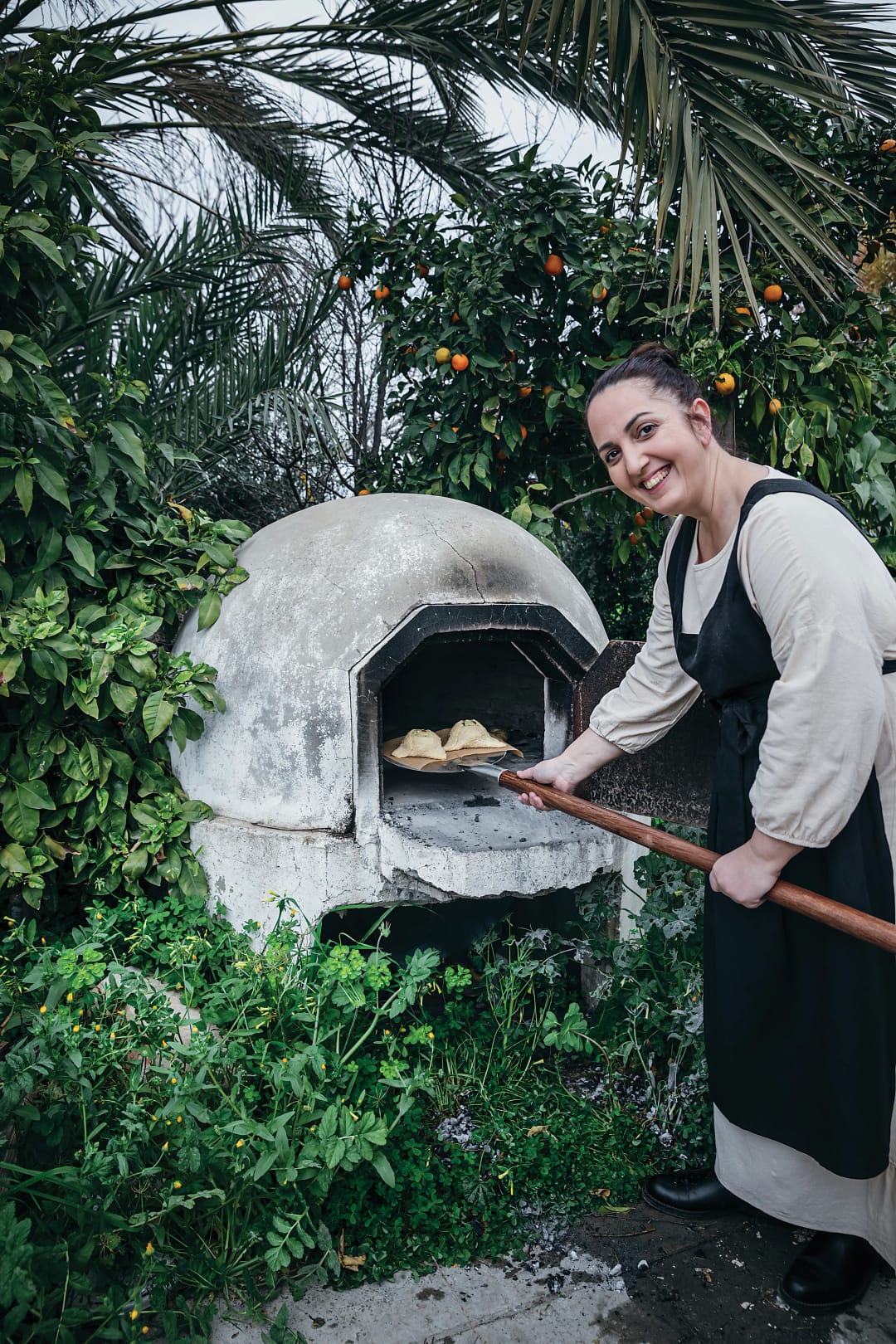 Chef Chryso baking bread in traditional outdoor oven